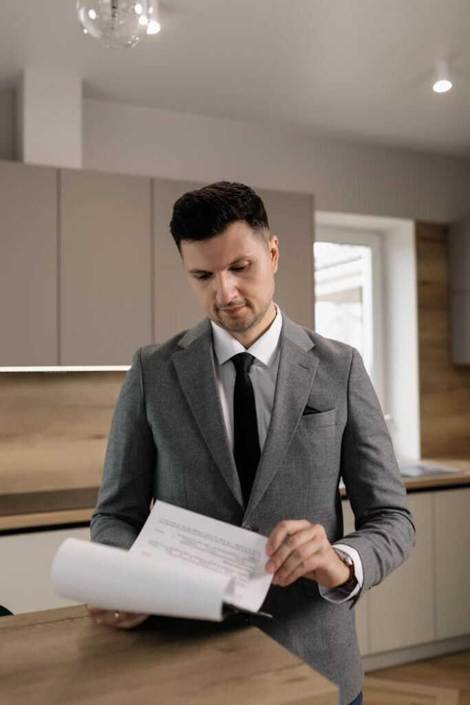 pexels-photo-7641840 Male real estate agent in suit reviewing property documents indoors.